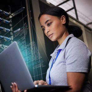 Pictorial representation of a woman standing in a server room holding a laptop that projects a digital code overlay.