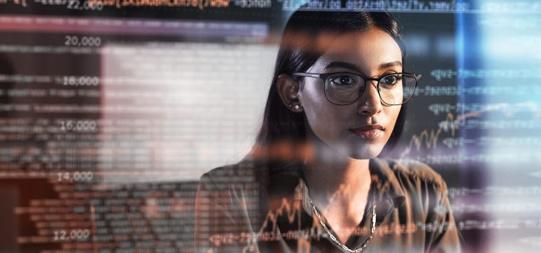 Pictorial representation of a woman in glasses viewing a reflection of a monitor screen. The reflection features multicolored numbers, arrows, and graphs.